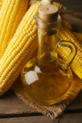 Wall Mural - Fresh corn with bottle of oil on table close up