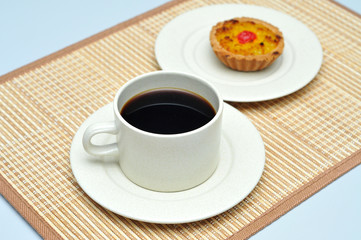 hot coffee with coconut tart on bamboo mat