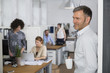 © Westend61 - Smiling man in office with colleagues in background