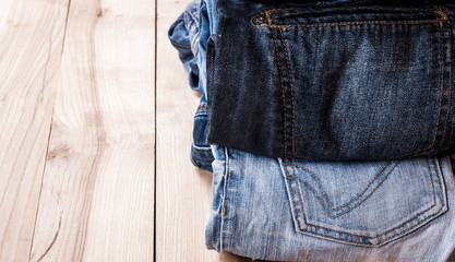 Poster - fashionable clothes. pile of jeans on a wooden background