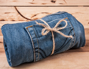 Sticker - fashionable clothes. pile of jeans on a wooden background