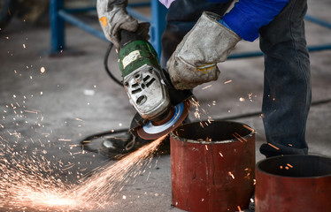 Electric wheel grinding on steel pipe in factory