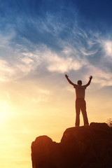 Wall Mural - silhouette of a man with raised-up arms at the sunset