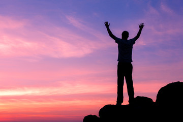 Wall Mural - silhouette of a man with raised-up arms at the sunset