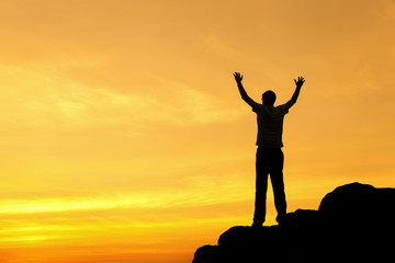 Wall Mural - silhouette of a man with raised-up arms at the sunset