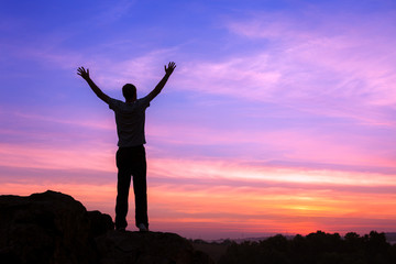Wall Mural - silhouette of a man with raised-up arms at the sunset