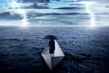 Asian Business Woman Holding Umbrella Alone On The Sea, Sailing With Paper Boat