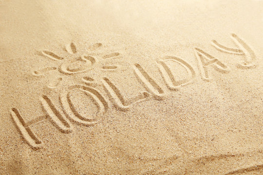Holiday handwritten in a beach sand