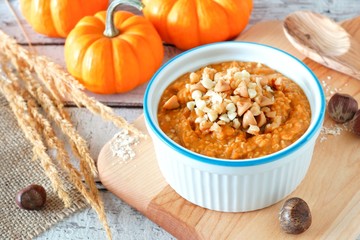 Wall Mural - bowl of autumn pumpkin oatmeal with walnuts, chocolate and peanut butter chips, table scene