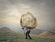 Businessman carrying a big rock