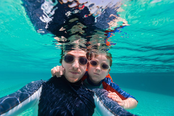 Wall Mural - Father and son swimming underwater