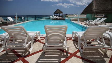 Wall Mural - Santa Claus Hat on sunbed near swimming pool. Christmas vacation concept