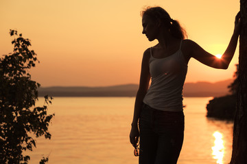 Wall Mural - Silhouette of woman who standing on the coast of lake