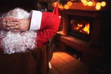 Santa Claus Resting In A Chair In Front Of A Fireplace