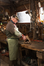 A Grandfather Is Working On A Wooden Birdhouse In His Workshop.