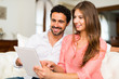 © Minerva Studio - Couple using a tablet while sitting on the couch in their home