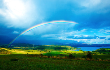   meadow and lake with mountain on background  a rainbow 