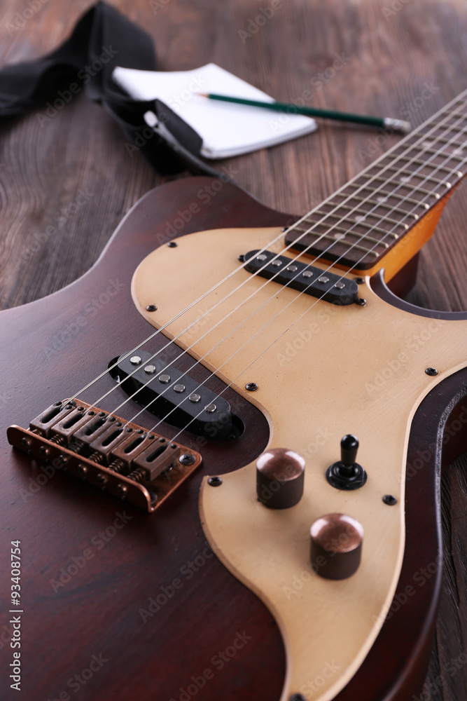 Electric guitar with notebook on wooden table close up