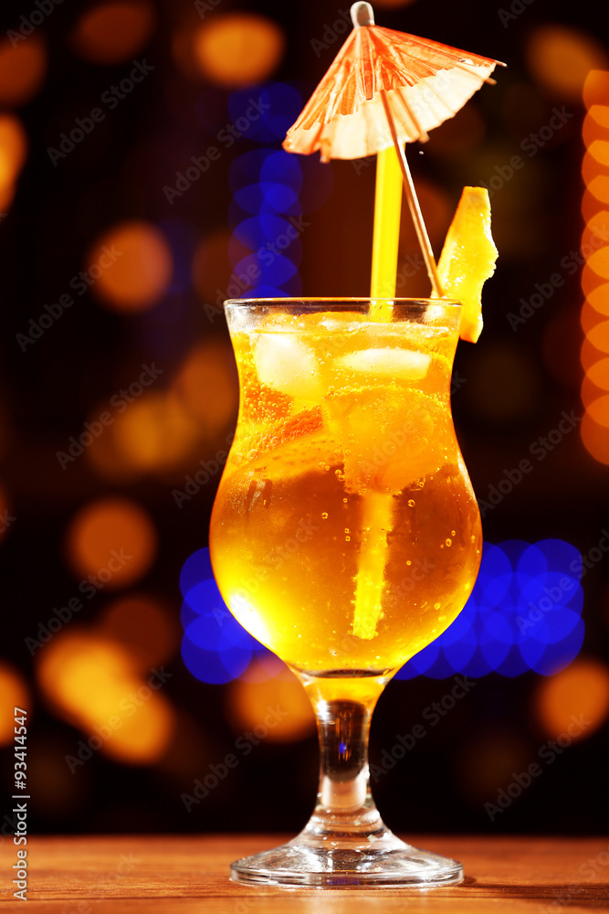 Glass of cocktail on dark blurred lights background