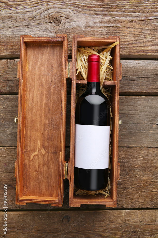 Expensive wine in elegant case with straw on wooden background