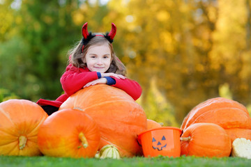 little girl wearing halloween costume on a pumpkin patch