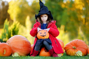little girl wearing halloween costume on a pumpkin patch