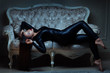 Girl in latex suit is lying on the sofa.
