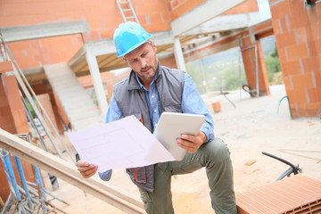 Construction manager checking blueprint on site