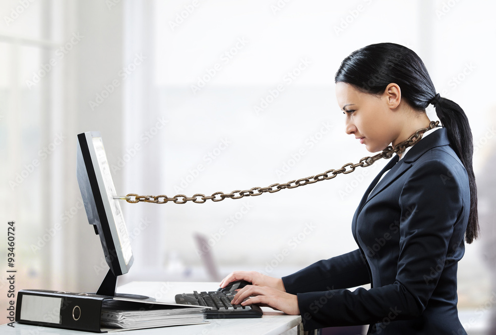 Female office worker chained to her computer - obrazy, fototapety, plakaty 