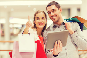 Poster - couple with tablet pc and shopping bags in mall