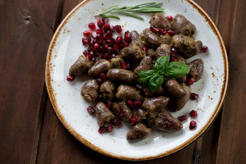 Wall Mural - Top view of roasted chicken hearts with pomegranate, studio shot