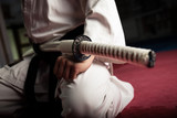 Close up of young martial arts fighter with katana siting in seiza position
