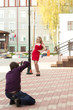 © tumbartsev - The photographer in the street taking pictures of the girl in the red dress by the lamppost