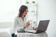 © undrey - young business woman working at desk typing on a laptop in