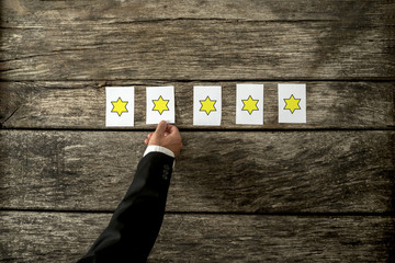 Wall Mural - overhead view of male hand placing five cards with golden stars