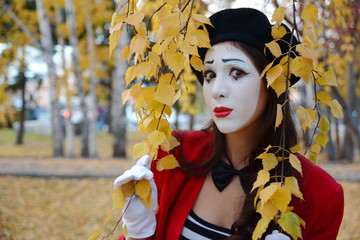 the girl is MIME peeks out from behind the yellow leaf