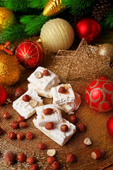 Wall Mural - Sweet nougat with hazelnuts and Christmas decoration table close up
