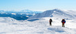 Two tourists walking on snow-covered mountain ridge towards the summit. The sky is clear, sunny. Winter. Ukraine