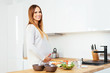© baranq - Smiling pregnant woman standing in the kitchen