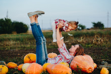 Mother And Daughter Lie Between Pumpkins