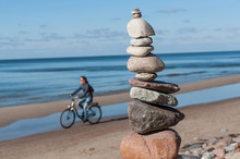 Stones Pyramid With Cyclist At Sea.
