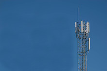  Telecommunications Tower With Many Phone Antennas And Blue Sky Background In The Morning.