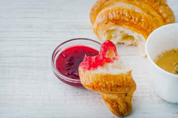 Wall Mural - Croissant dipped in berry jam with cup of coffee