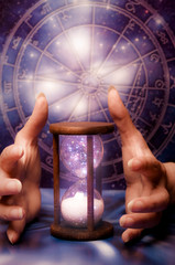 woman hands with an hourglass over a zodiac chart