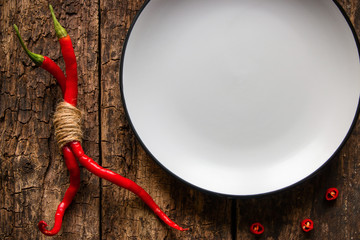 two related pod of red pepper next to an empty white plate