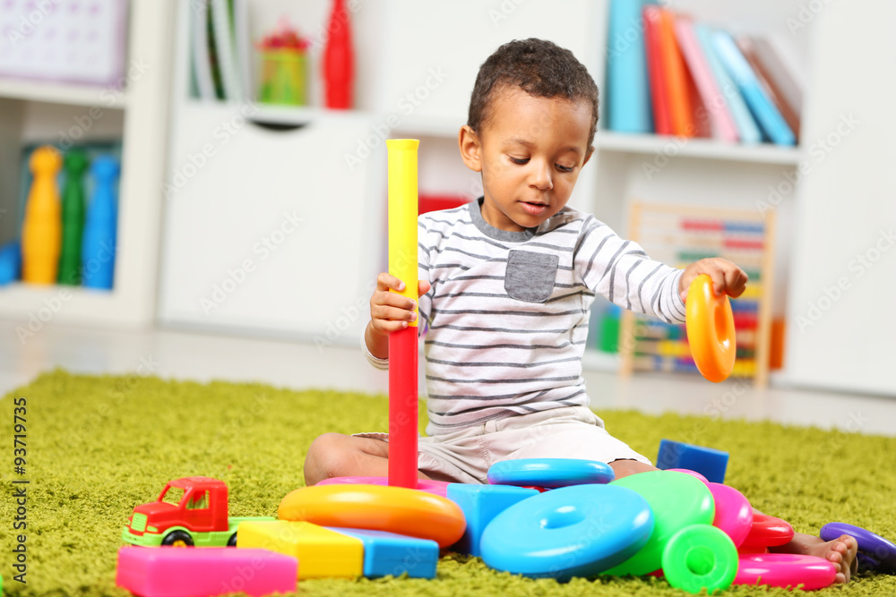 Little boy playing with his toys in the room