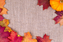 Background From Autumn Leaves And Pumpkin On Burlap