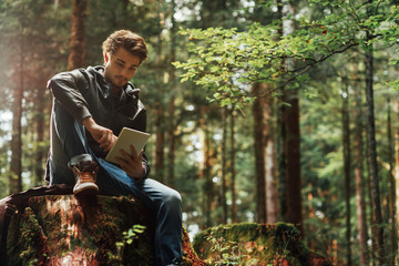 Wall Mural - Young man using a digital tablet in the woods