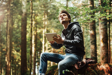 Wall Mural - Young man using a digital tablet in the woods