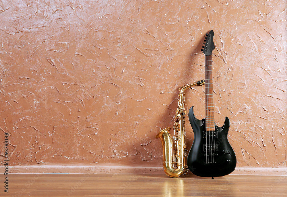 Electric guitar and saxophone on brown wall background